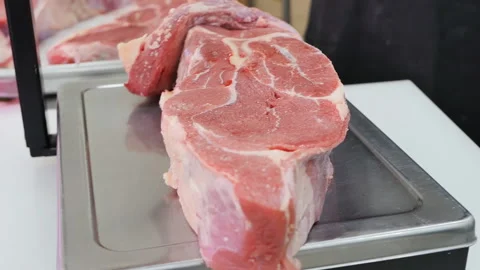 The butcher put a large piece of red beef meat on the scales to be weighed and p Stock Footage 231579419