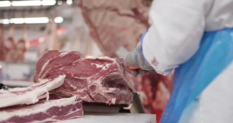 Butcher trimming a large beef piece in a meat processing hall, Food Factory 库存影片 340019413