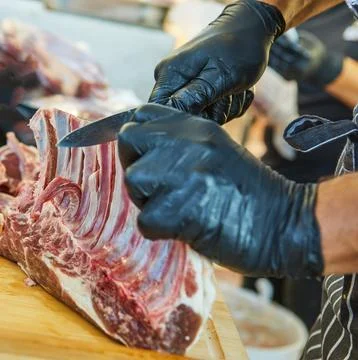 Butcher trimming raw ribs with knife Stock-Fotos