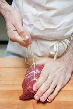 Butcher tying beef tenderloin with string Foto stock