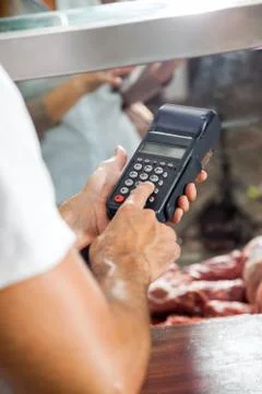 Butcher Using Electronic Card Machine In Shop Foto stock