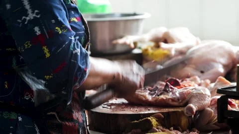 Butcher wearing patterned apron slicing whole raw chicken meat with sharp c.. Stock Footage 344815999