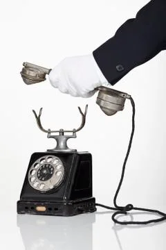 A butler holding the receiver of a rotary phone, focus on hand Stock Photos
