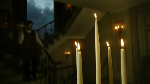 Butler serving in a villa bringing dish at evening with lighted candles Stock Footage
