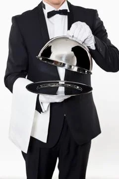 A butler taking the domed lid off an empty silver tray Stock Photos