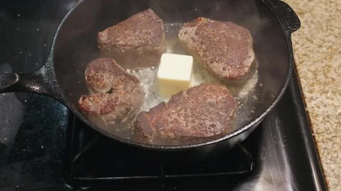 Butter basting four steak fillets in a cast iron skillet Stock Footage 326092763