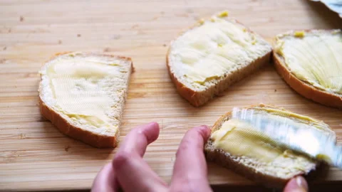 Butter bread sandwich hand spreading dairy by knife on wooden cutting board Vídeo Stock 311284356