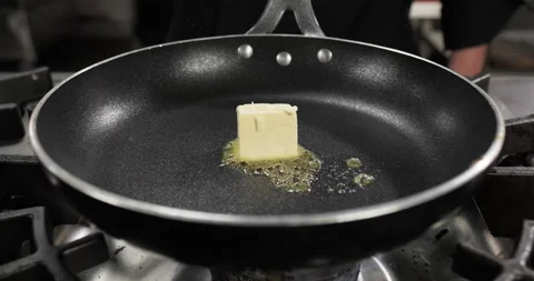 Butter cube melting sizzling in a wok pan on a gas stove Stock-Footage 295956485