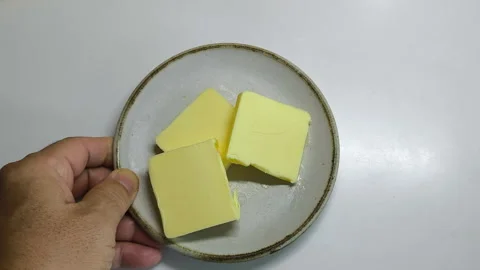 The butter is cut into small, ready-to-use pieces on a white plate. Stock Footage 318009638