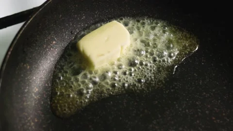 Butter is fried in a dark non-stick pan. Butter is melted in a hot pan Stock Footage 131191553