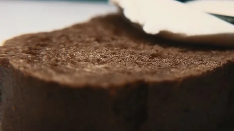 Butter knife rubs butter or cottage cheese on piece of bread. Tilt shift Stock Footage