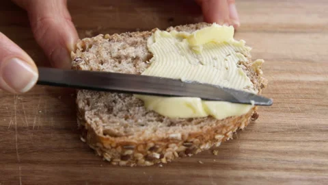 The butter is spread over the bread with a knife. Stock Footage 149603415