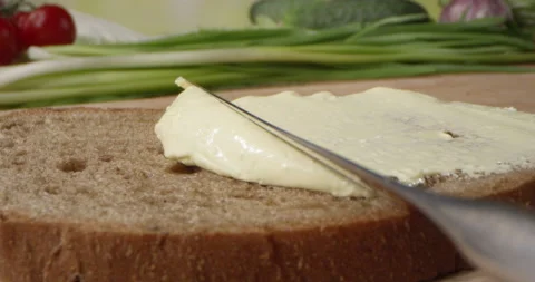 Butter Spread is Spreading on a Bread Slice with a Knife on a Cutting Board Stock Footage 154045435