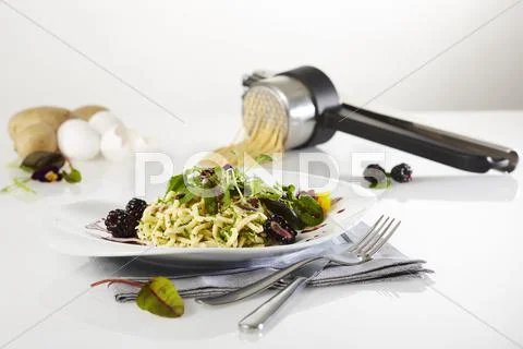 Buttered egg noodles with a wild herb salad and a blackberry dressing Stock Photos