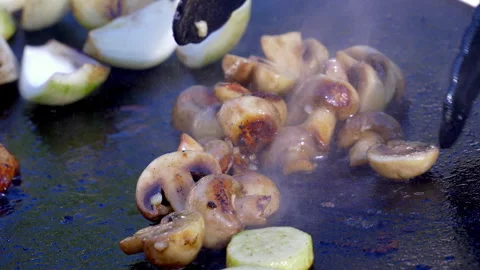 Button mushrooms are being fried on an outdoor griddle. Stock Footage 346186904