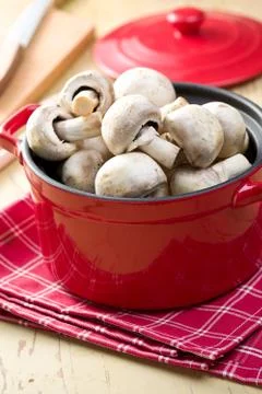 Button mushrooms in red pot Stock Photos