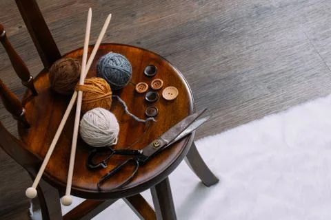 Button, scissors and yarn ball on wooden chair 库存照片