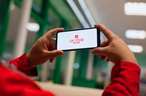 Button on the screen of a mobile phone. A man watches a live broadcast on a Stock Photos