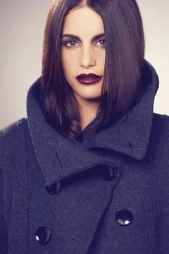 Button up. Studio shot of a stylishly dressed young woman against a gray back Stock Photos