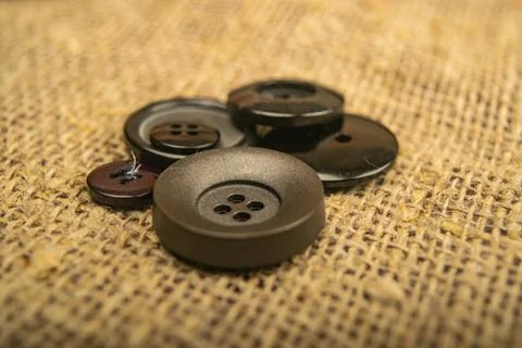 Buttons of different sizes on burlap with a rough texture. Close up. Stock Photos