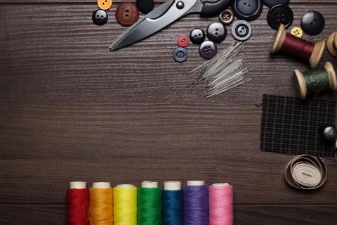 Buttons, needles and multicolored threads on wooden table Foto stock
