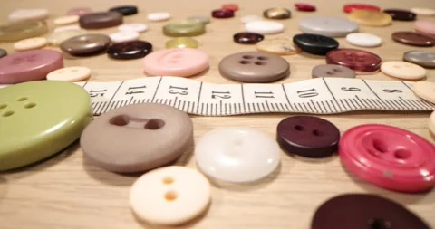 Buttons, needles, pins, spools and tailor's tape on wooden desk, close up. Stock Footage 168249354