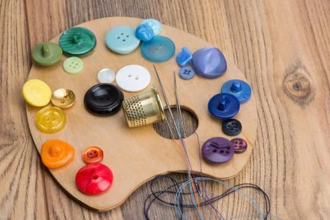 Buttons, thimble, needle and thread on the palette Stock Photos
