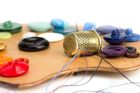 Buttons, thimble, needle and thread on the palette Stock Photos