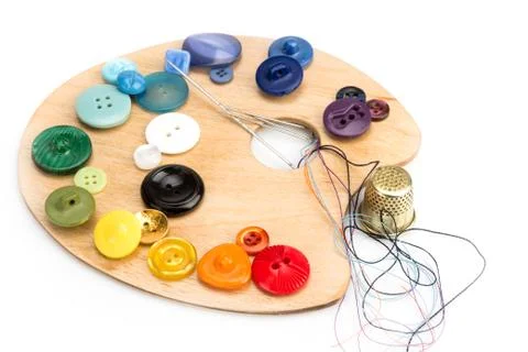 Buttons, thimble, needle and thread on the palette Stock Photos
