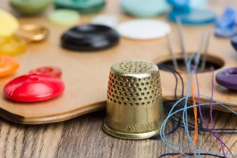 Buttons, thimble, needle and thread on the palette Stock Photos