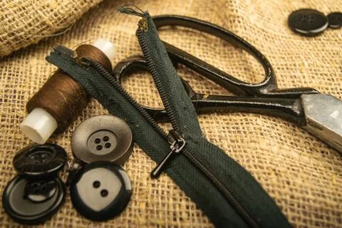 Buttons of various sizes, a spool of thread, tailor's scissors, and a zipper  Stock Photos