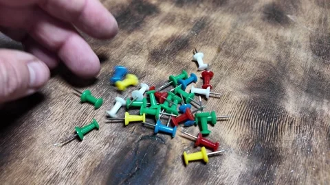 Buttons on a wooden table. collect push pins that fall apart on a wooden ta.. Stock Footage 292386576