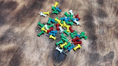 Buttons on a wooden table. collect push pins that fall apart on a wooden table.  Stock Footage 292386918