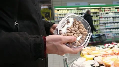 The buyer chooses nuts in plastic packaging Stock Footage 235215960