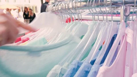 The buyer choosing in the shop looking through the female shirts Vídeos de archivo 80913468