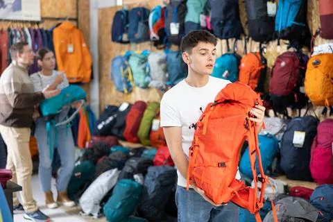 Buyer guy chooses summer backpack in store for hikes Stock Photos
