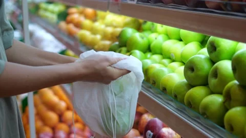 Buying fresh fruit and using eco bags. A woman buys a green apple to prepare Video stock 205021033