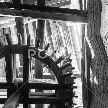 BW shot from below of aged water mill turning inside weathered mill building Stock Photos