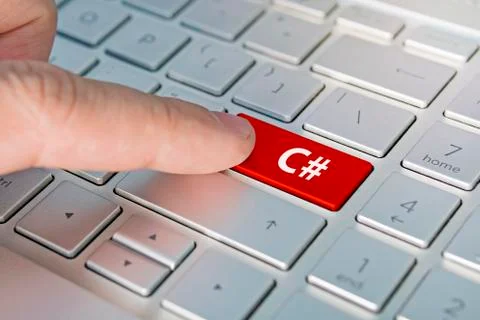 C# computer language. writing on button modern of gray laptop. Finger presses Stock Photos