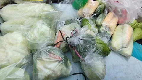 Cabbage, corn and cucumber vegetables wrapped in plastic are ready to be sold Stock Footage 219198126