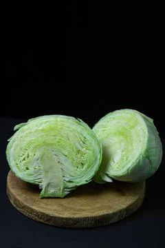 Cabbage on a dark background. Cabbage cut into two halves on a black background. Stock Photos