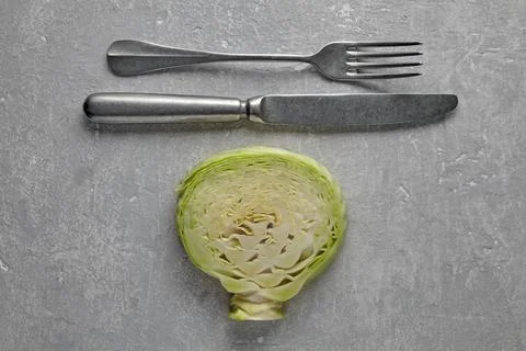 Cabbage leaf and cutlery fork with knife on gray table. weight loss diet co.. Stock Photos