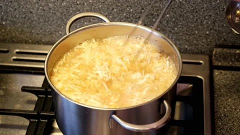 The cabbage is stirred in the boiling broth with long metal tongs Stockbeeldmateriaal 168412023