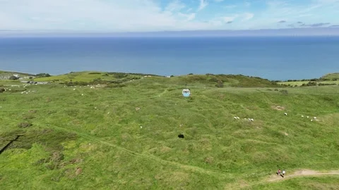 Cabel car ascent to summit with sea in back and green grass Stock Footage 276775603