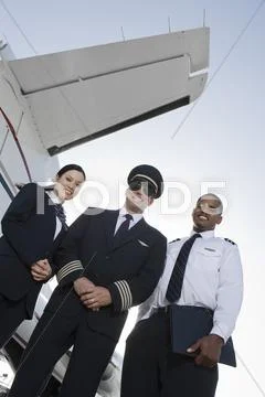 Cabin Crew Members Standing Together At Airfield Stock Photos