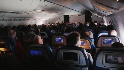 In the cabin of a large airliner. Passengers in comfortable armchairs watching Stock Footage 82013674