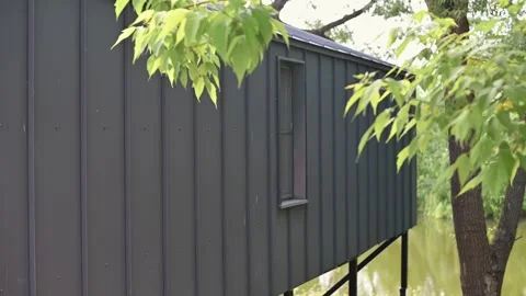 A cabin made of dark wood is elevated on stilts, surrounded by lush green trees. Stock Footage 339004538