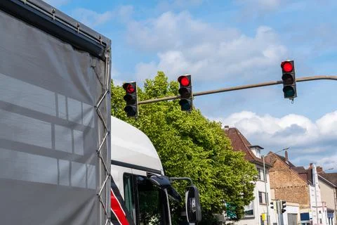 Cabin of a truck standing at an intersection in front of red traffic lights. Stock Photos