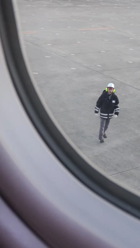 Cabin window view: a technician guiding pushback, Sendai, Japan, Mar 9, 2026. 库存影片 330539609