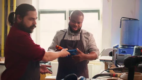 Cabinetmaker ensures apprentice uses safety earmuffs before starting work Video stock 271157330